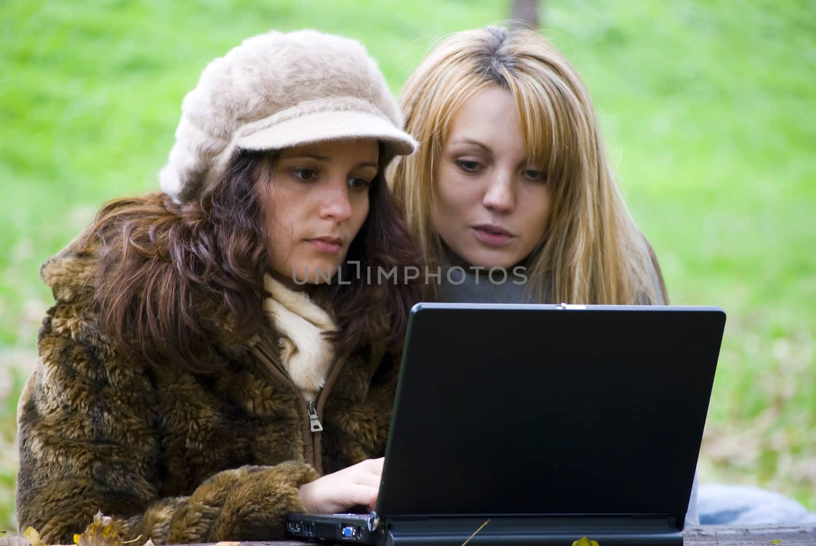 two students working out on laptop in autumn