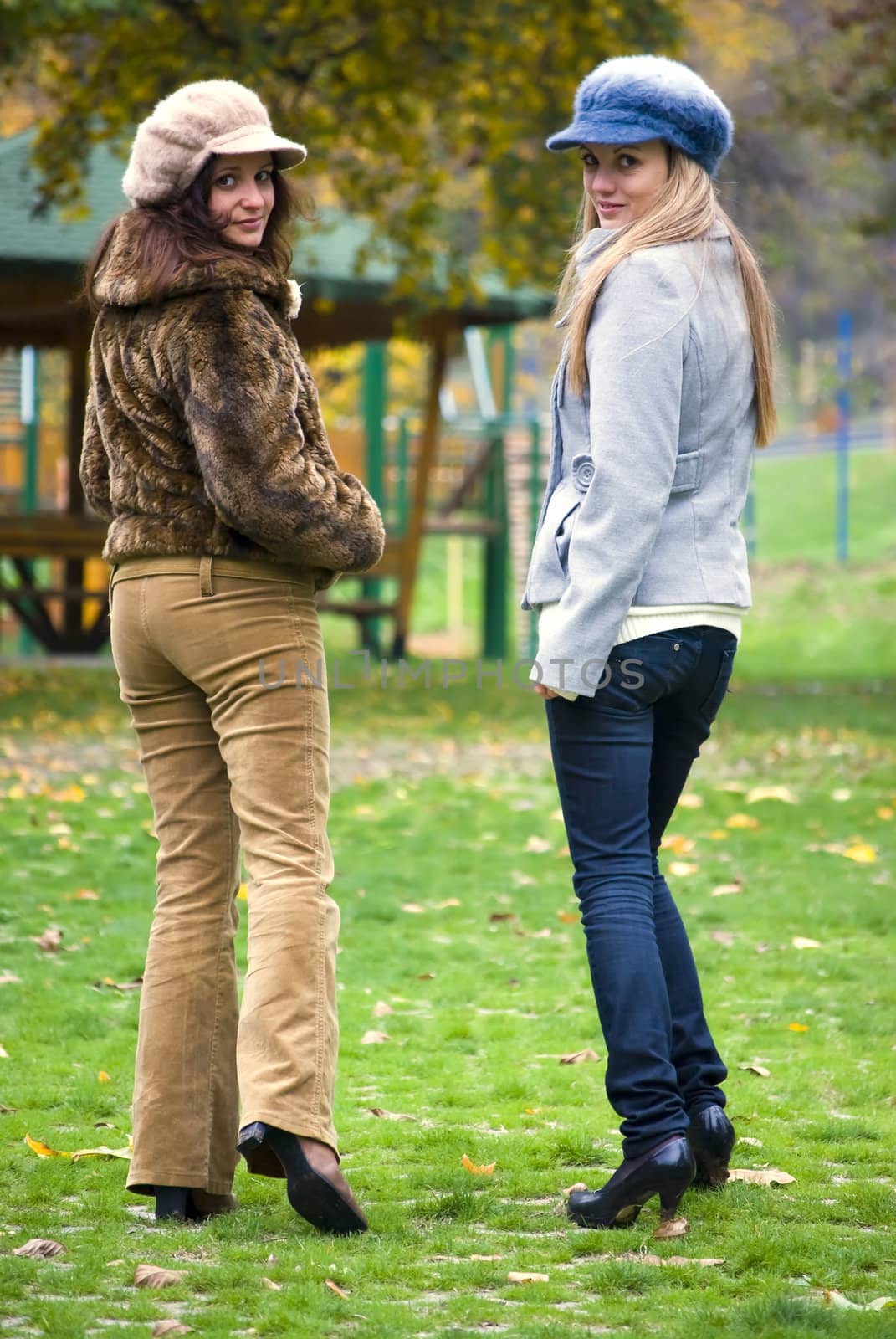 two cute women outdoors in autumn walking and looking back