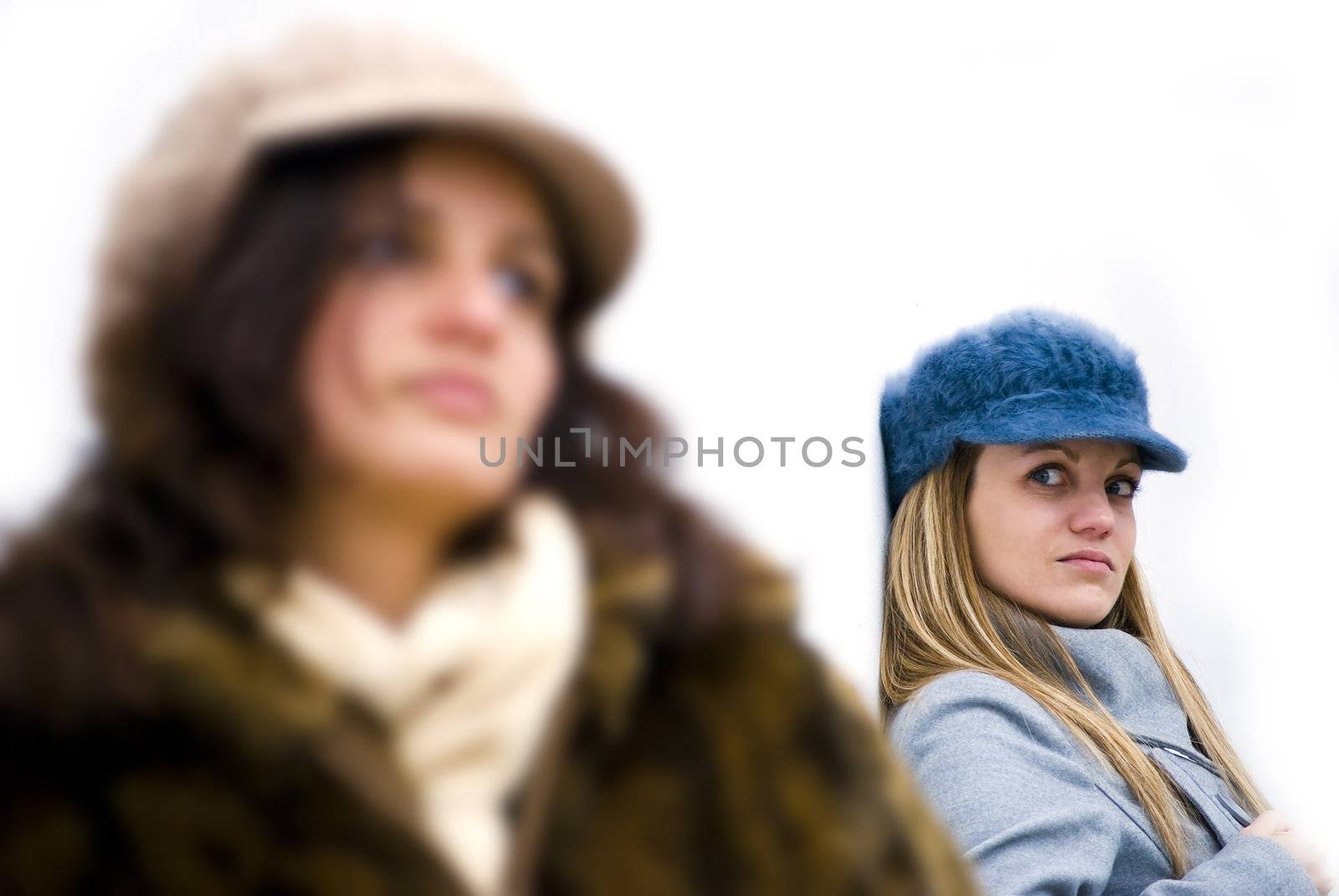 two girls being angry to each other posing on white wall