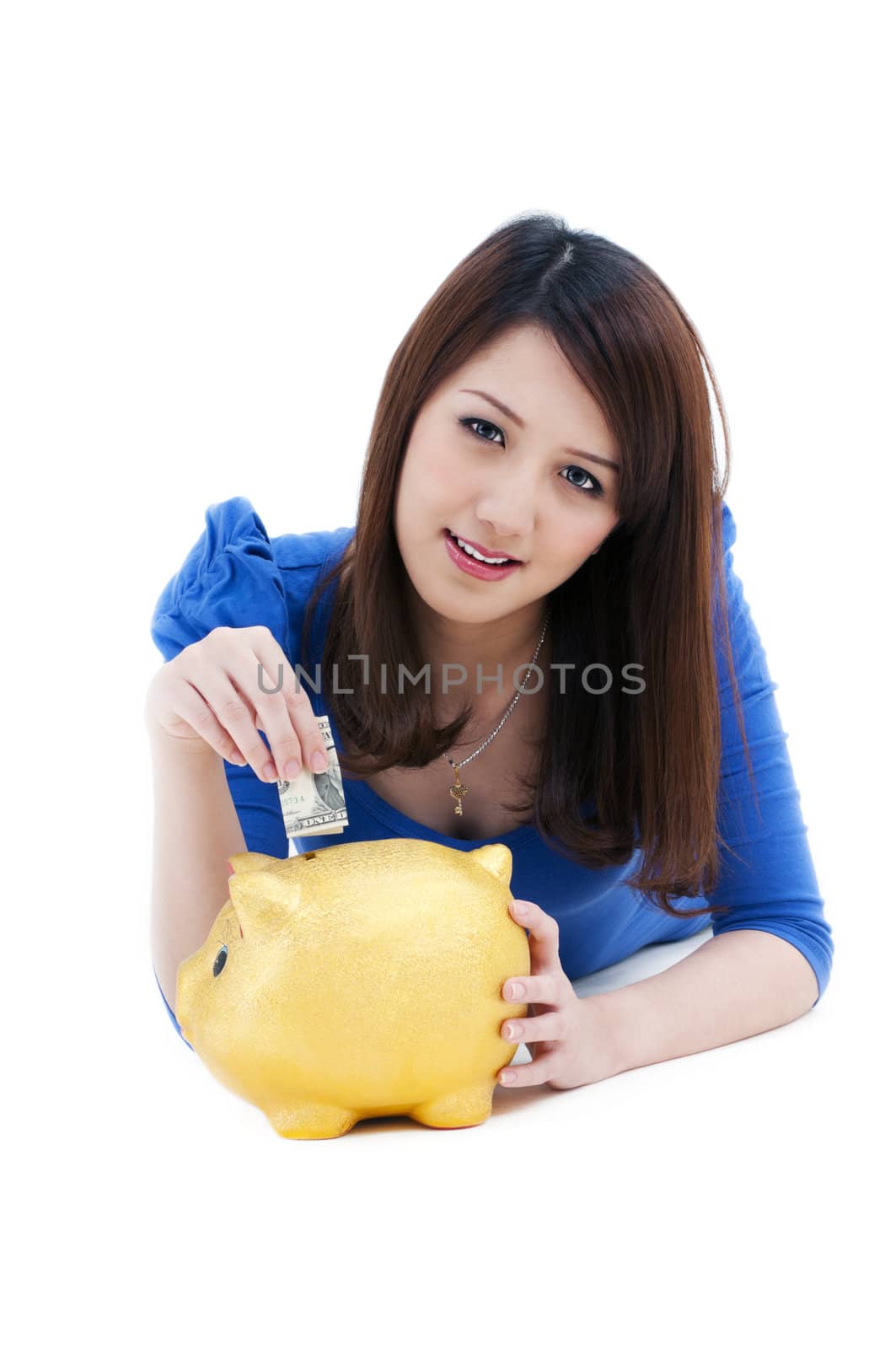 Portrait of an attractive young woman putting money into piggy bank over white background.