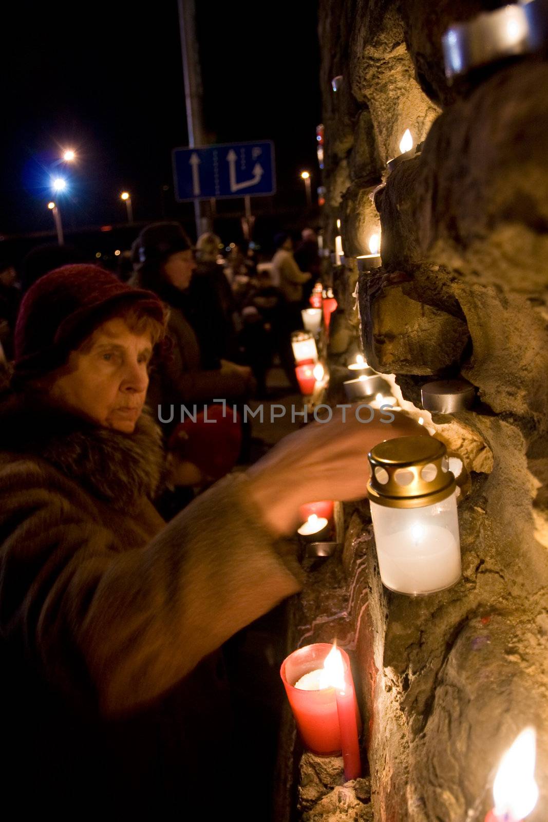 RIGA, LATVIA - NOVEMBER 11: Soldiers Memorial Day. Woman lights candle at Prezident's castle wall to commemorate victory over the Russian and German militia. This victory was important in the birth of Latvia as an independent nation. November 11, 2009 in Riga
