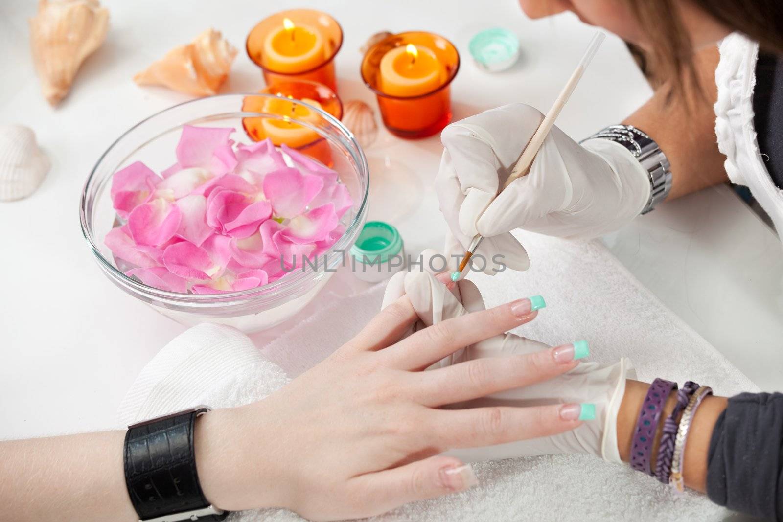 Beautician painting fingernail tips in green. Close-up shot