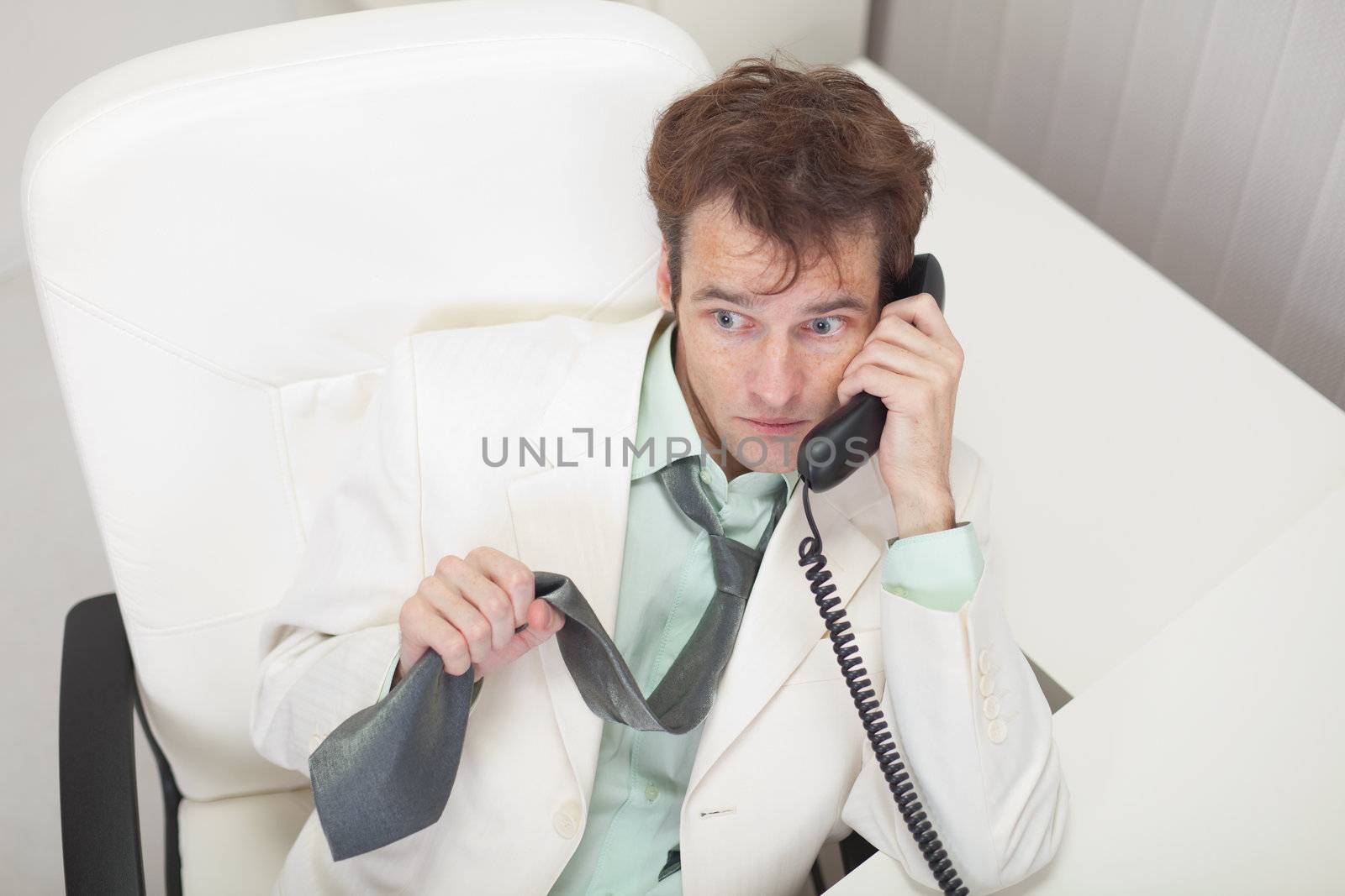 Businessman in white jacket emotionally talks by phone by pzaxe