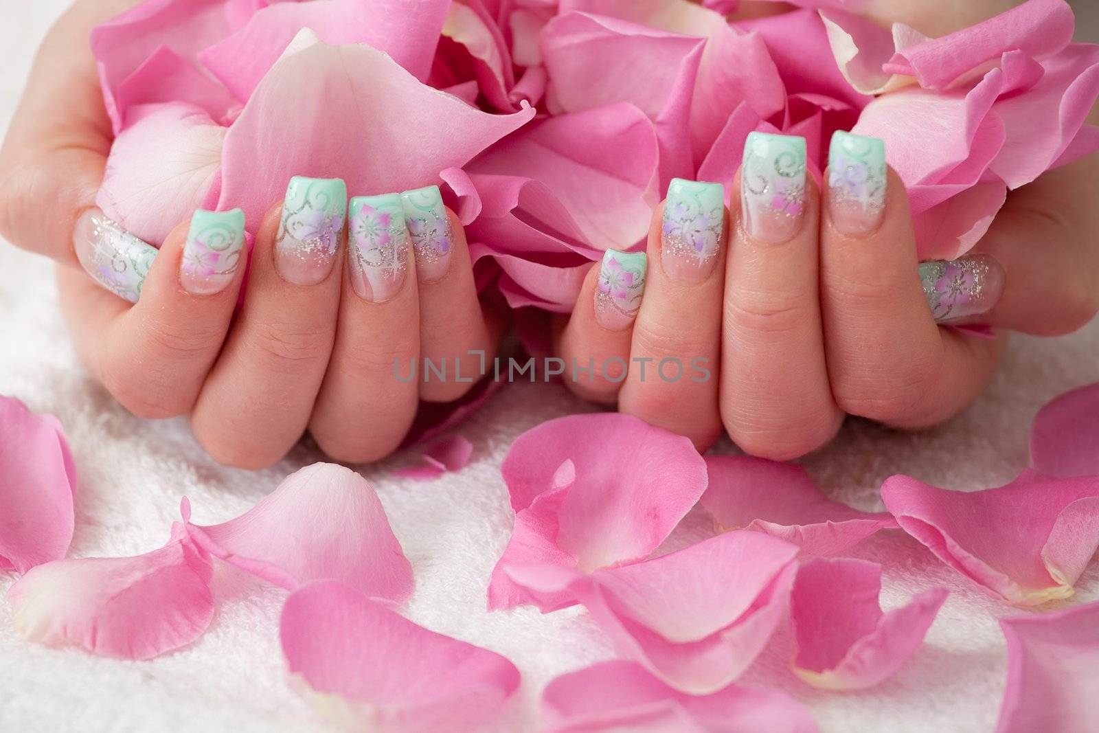 Holding pink rose petals. Artificial fingernail with airbrush pattern