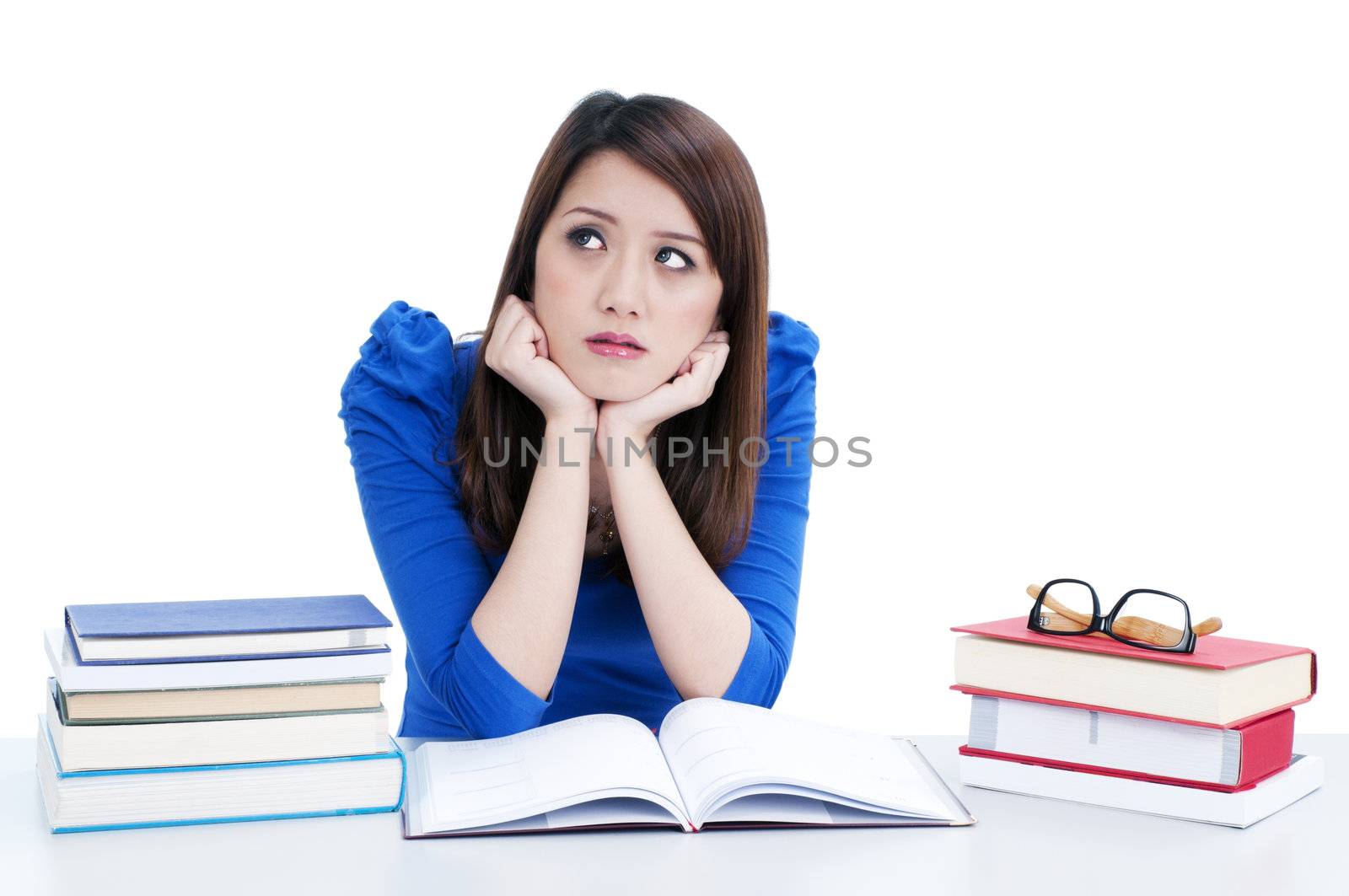 Portrait of a pensive female student with hands on chin over white background.