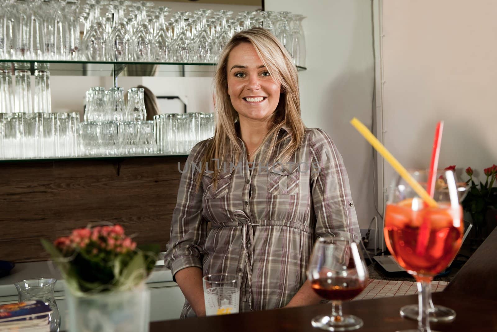 Cheerful bartender standing behind the counter and smiling