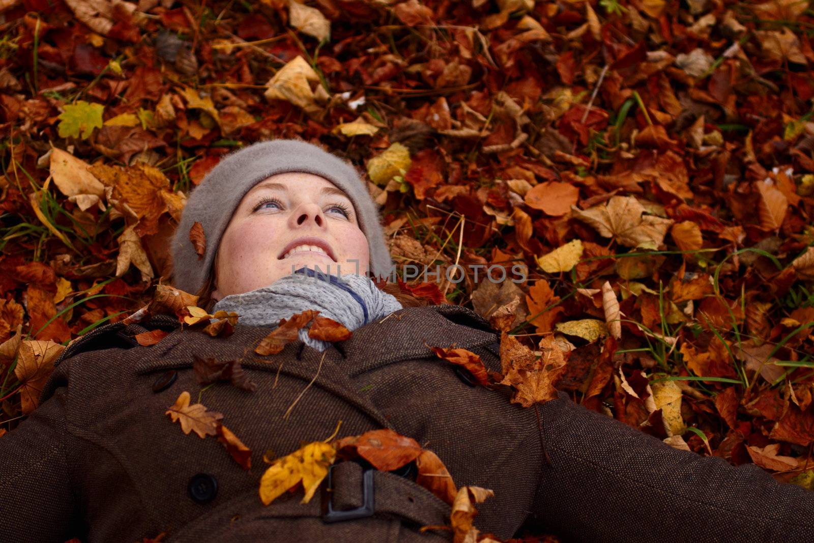 Autumn - young woman lying down in leaves