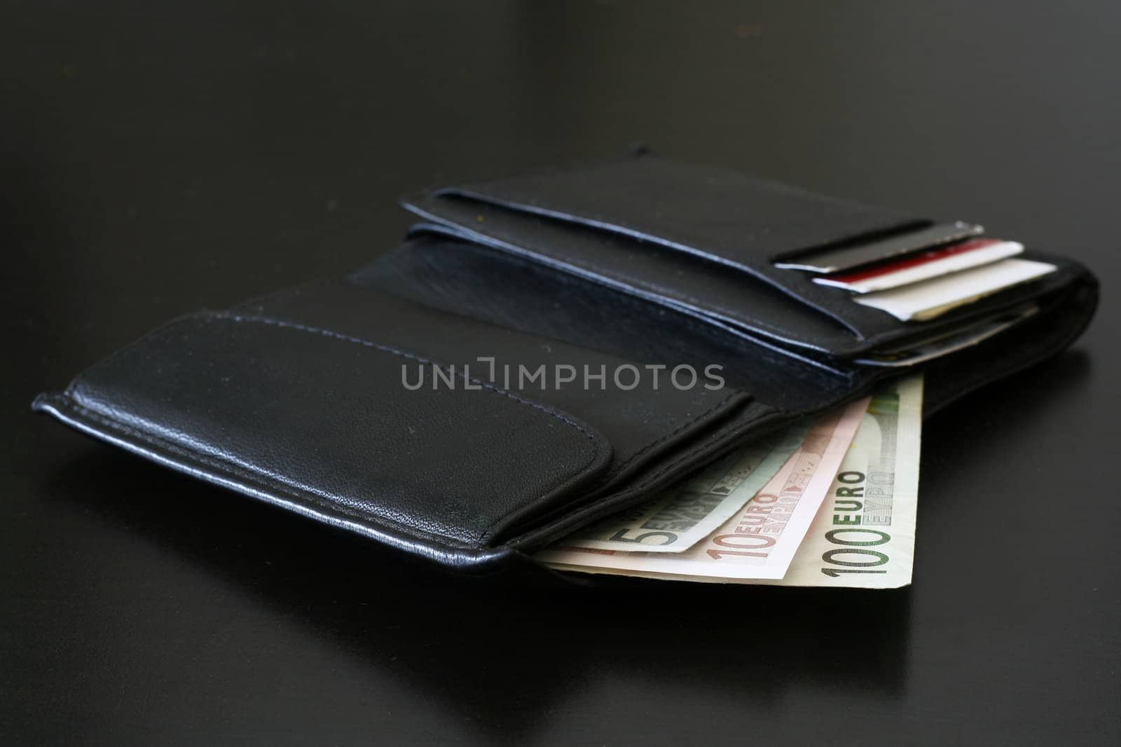 Euro bills coming out of a black wallet.