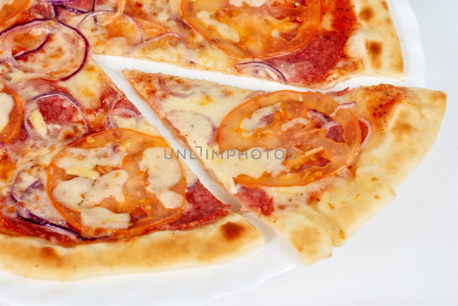 pizza closeup with salami, tomato, onion and mozzarella cheese