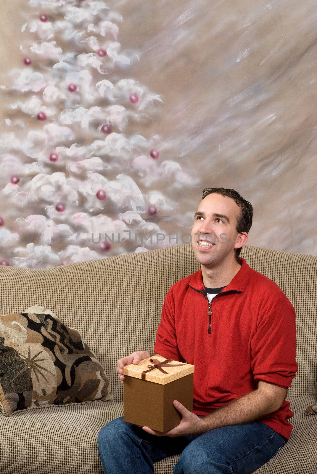 A man dressed in a red sweater and blue jeans is holding a Christmas present