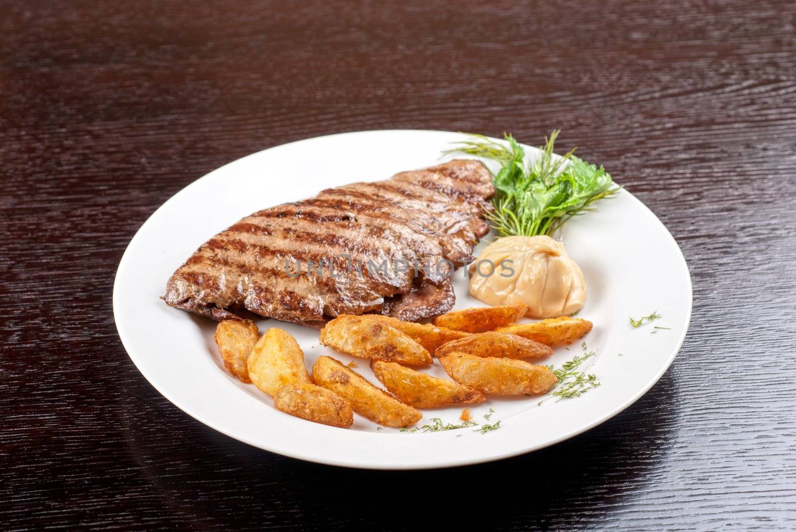 Juicy beef steak stuffed with beef tongue and cheese served with potatoes, greenery and sauce