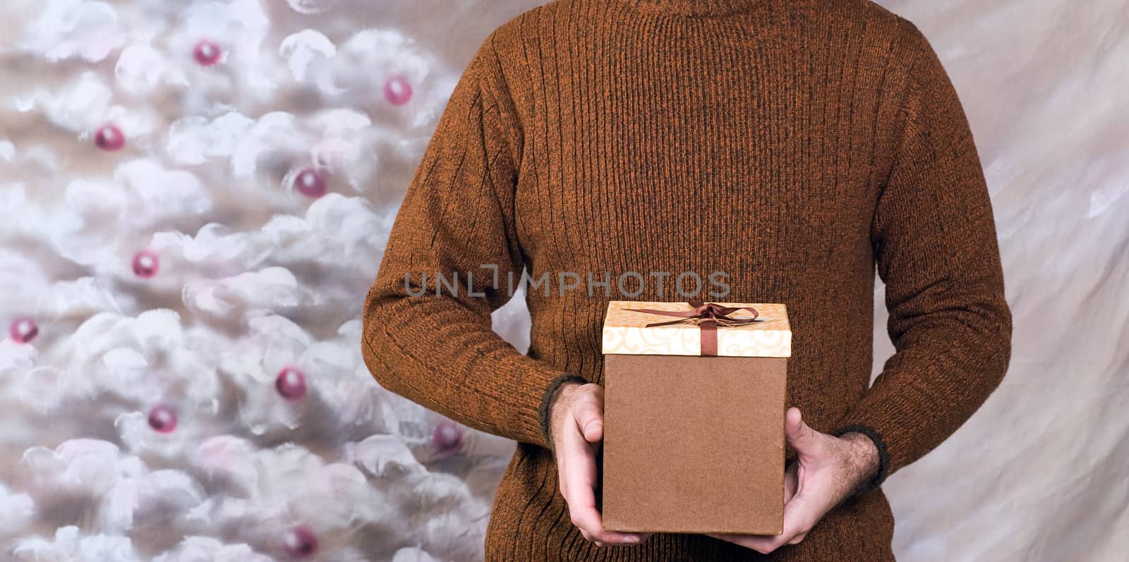 Closeup view of a young man wearing a sweater and holding a holiday gift