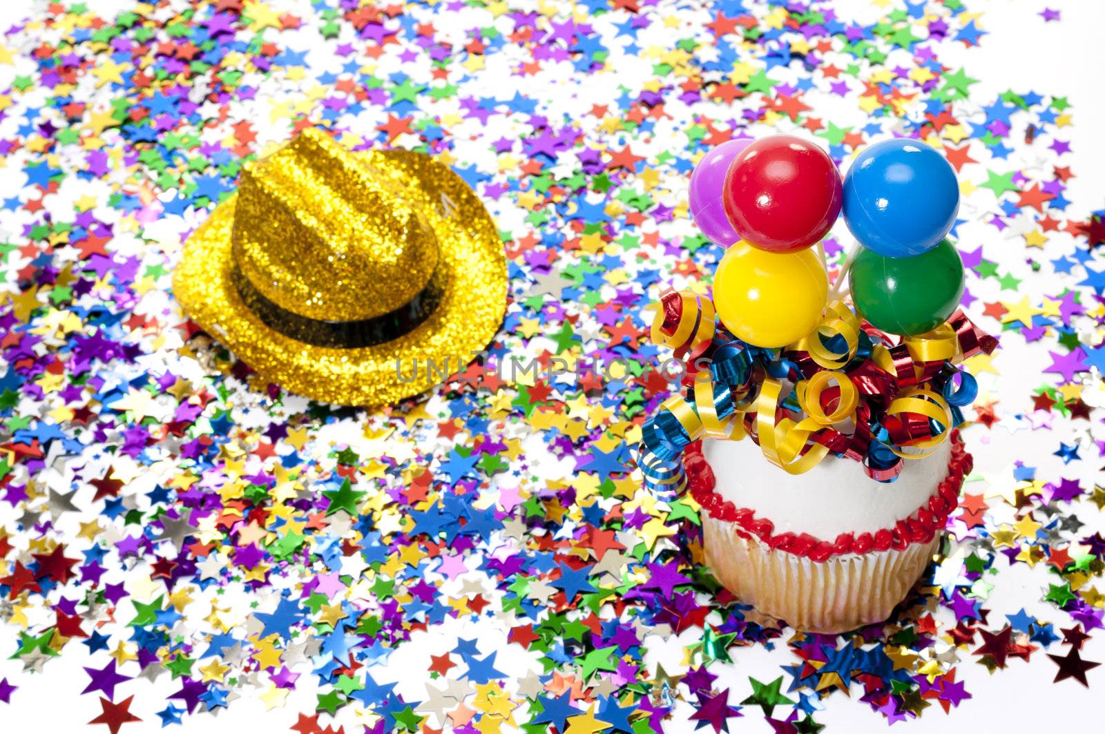 Decorated cupcake, confetti, and cowboy hat at party.