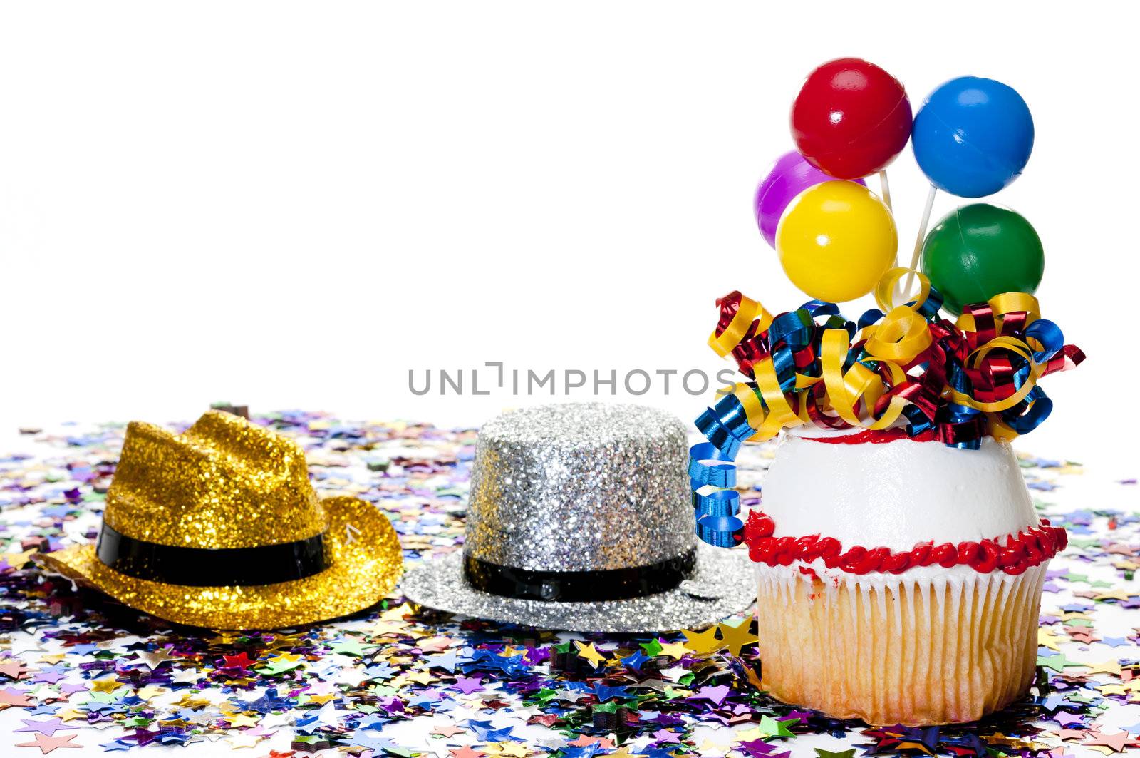 Decorated cupcake, confetti, and cowboy hats at party.