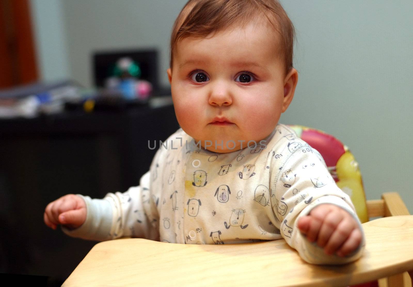 Little babe sits in wooden chair at home