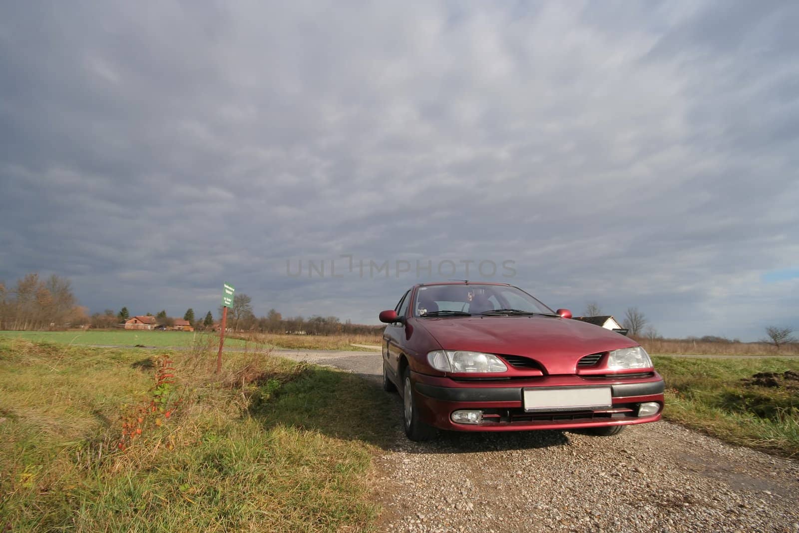 Car on path with stormy clouds