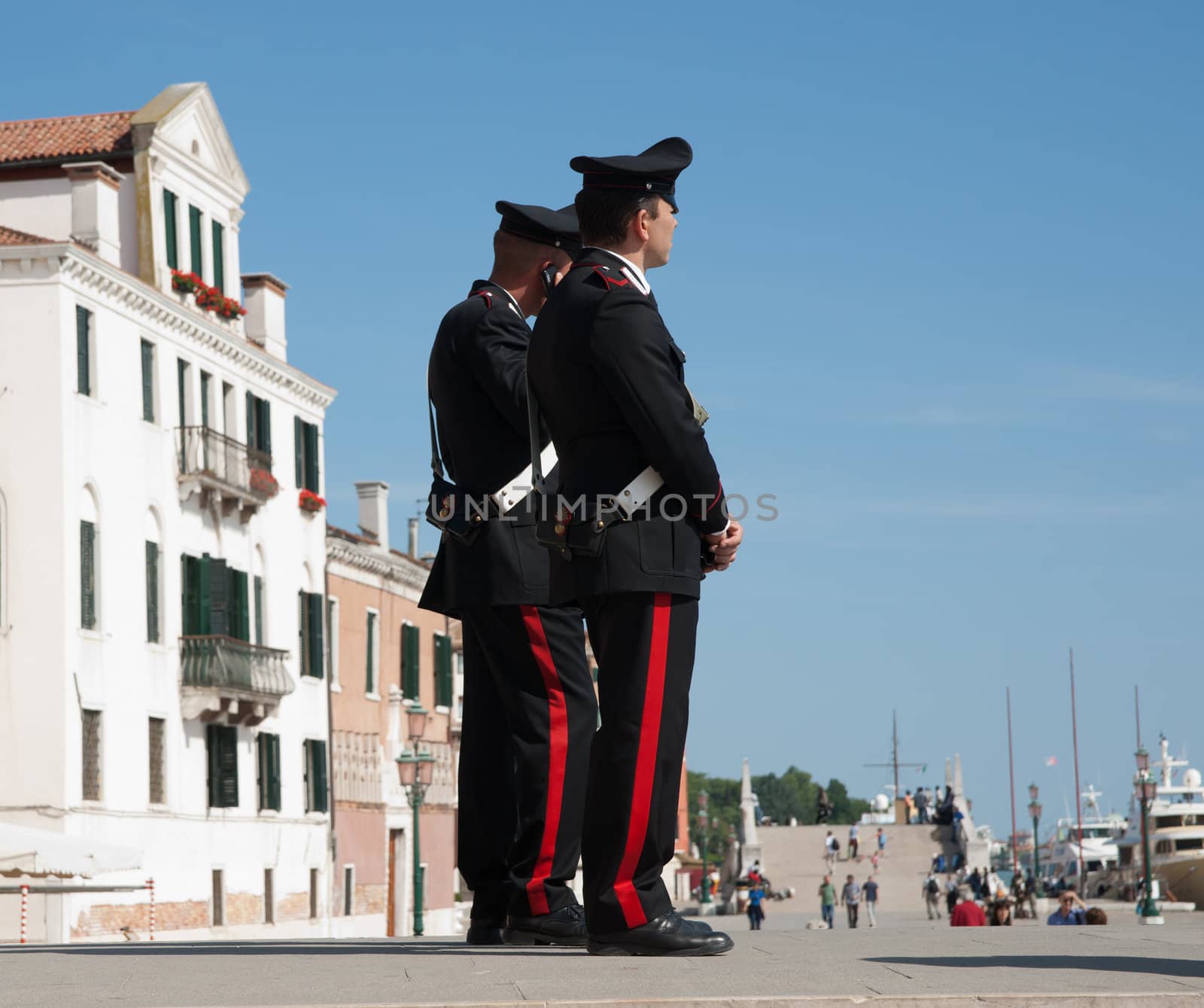 Two Italian police, carabinieri, stand uniformed watching the Venice tourists on Ponte della Paglia, Riva degli Schiavoni, Venice's waterfront promenade, May 2011.