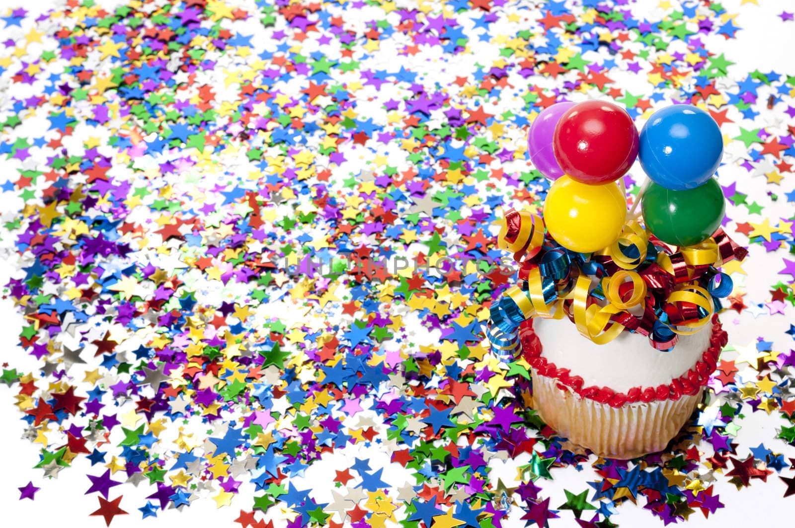 Decorated cupcake with balloons and ribbon with confetti at party.