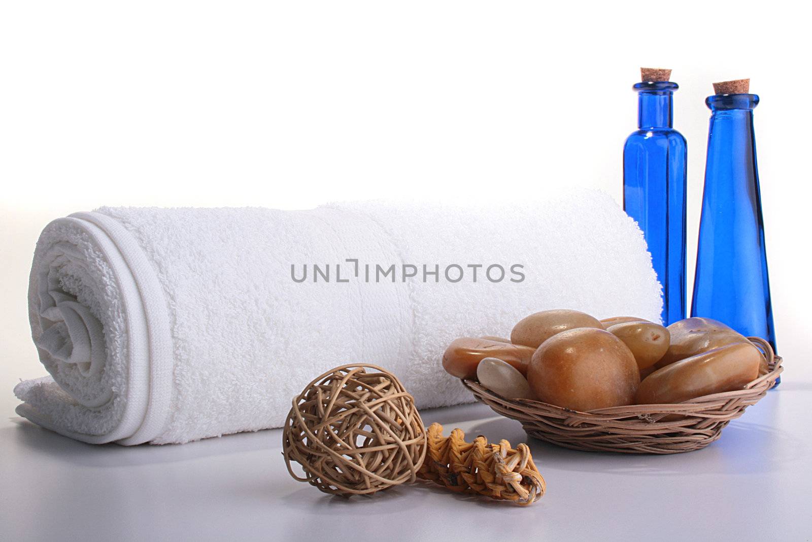 Two bottles of dark blue glass, towel it is curtailed into a roll, sea stones in a basket and an aromatic tree.