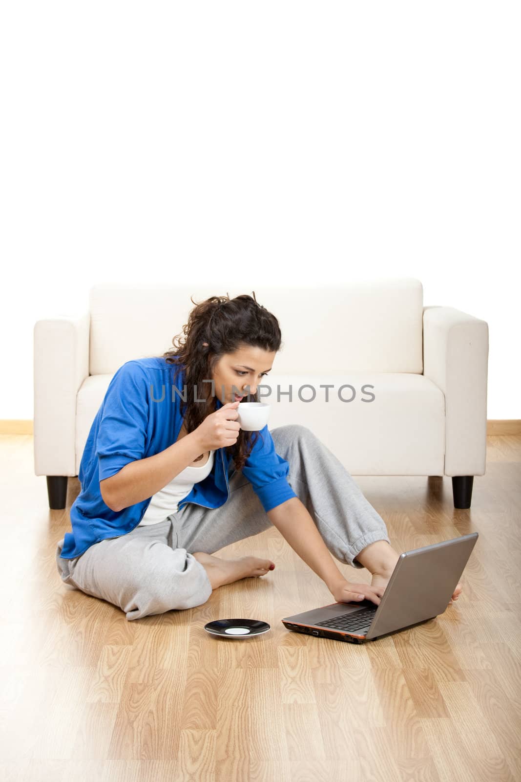 
Portrait of a girl seated on floor and using laptop with a cup of coffee
