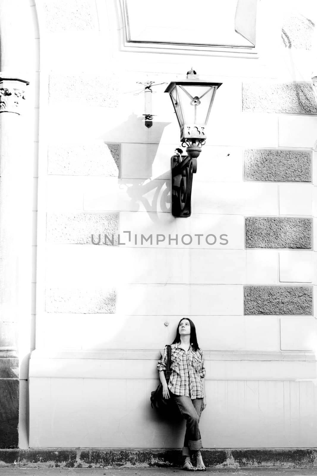 Girl standing near wall under lamp
