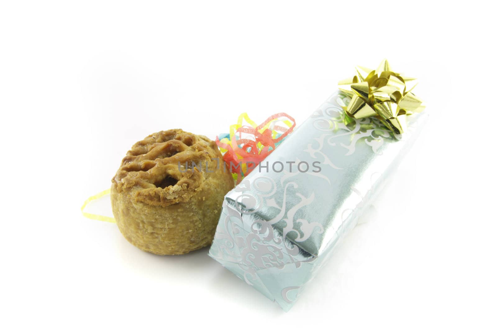 Small pork pie with a silver shiny gift and streamers on a reflective white background