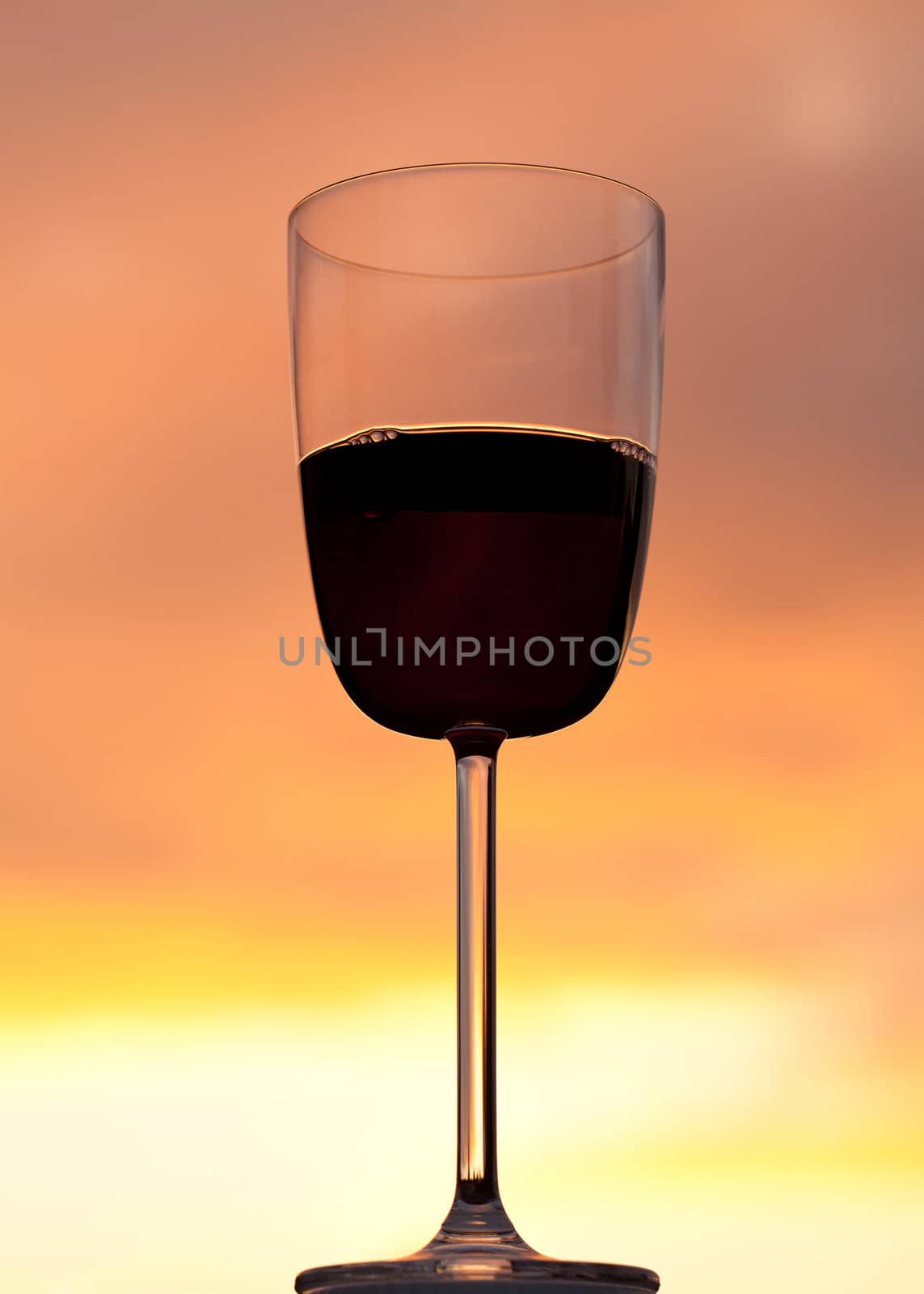 Sunset behind glass of red wine by steheap