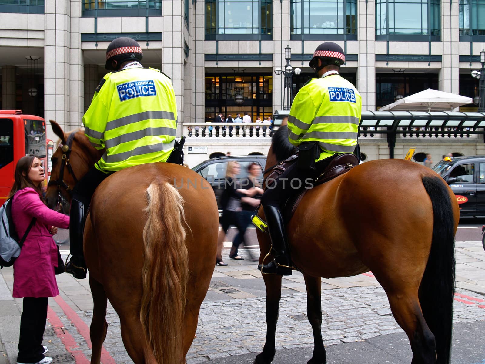 Mounted police in streets of London, England providing a law- keeping presence in 2009 talking with w woman in pink coat.The mounted unit was used in the recent London riots.