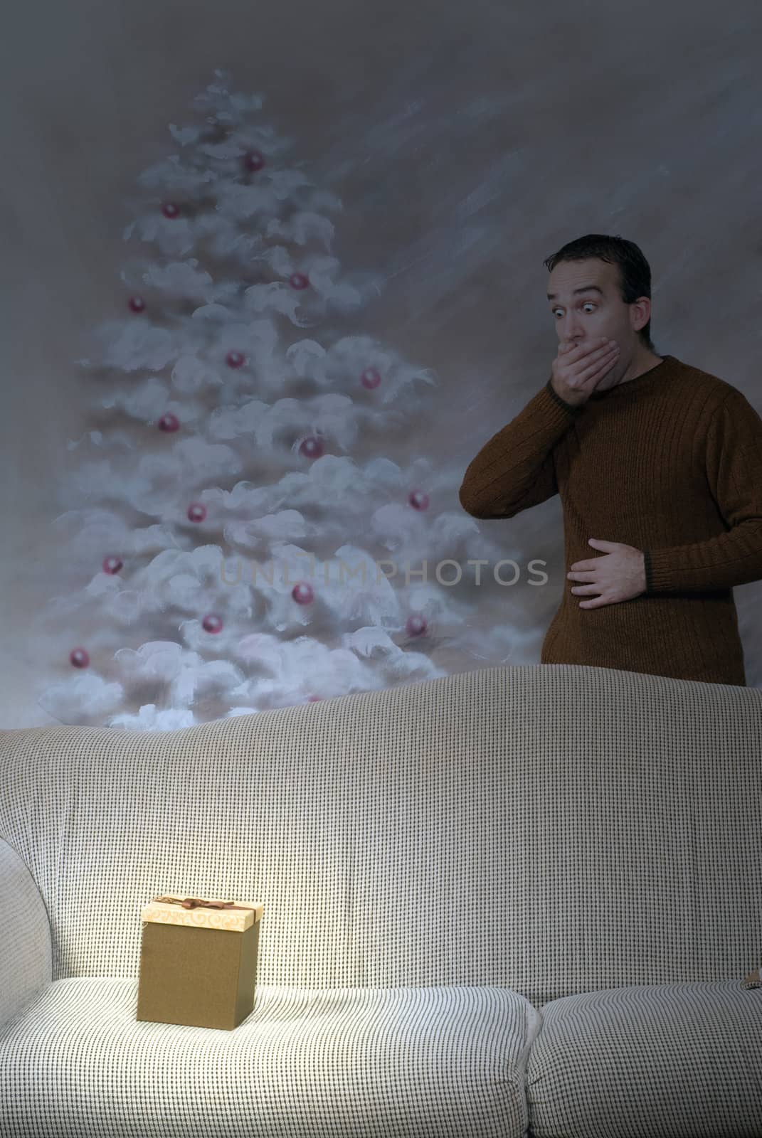 A christmas box is glowing at night in the living room, with a man covering his mouth in surprise