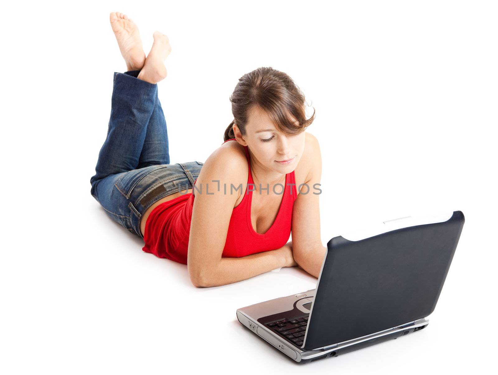 Beautiful young woman lying on floor and working on a laptop