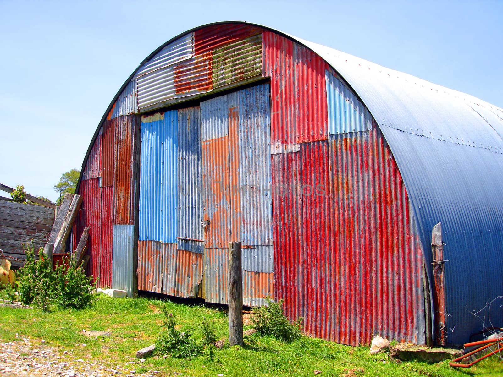 Round Metal Shed on Farm with Mismatched Paint on front surface.