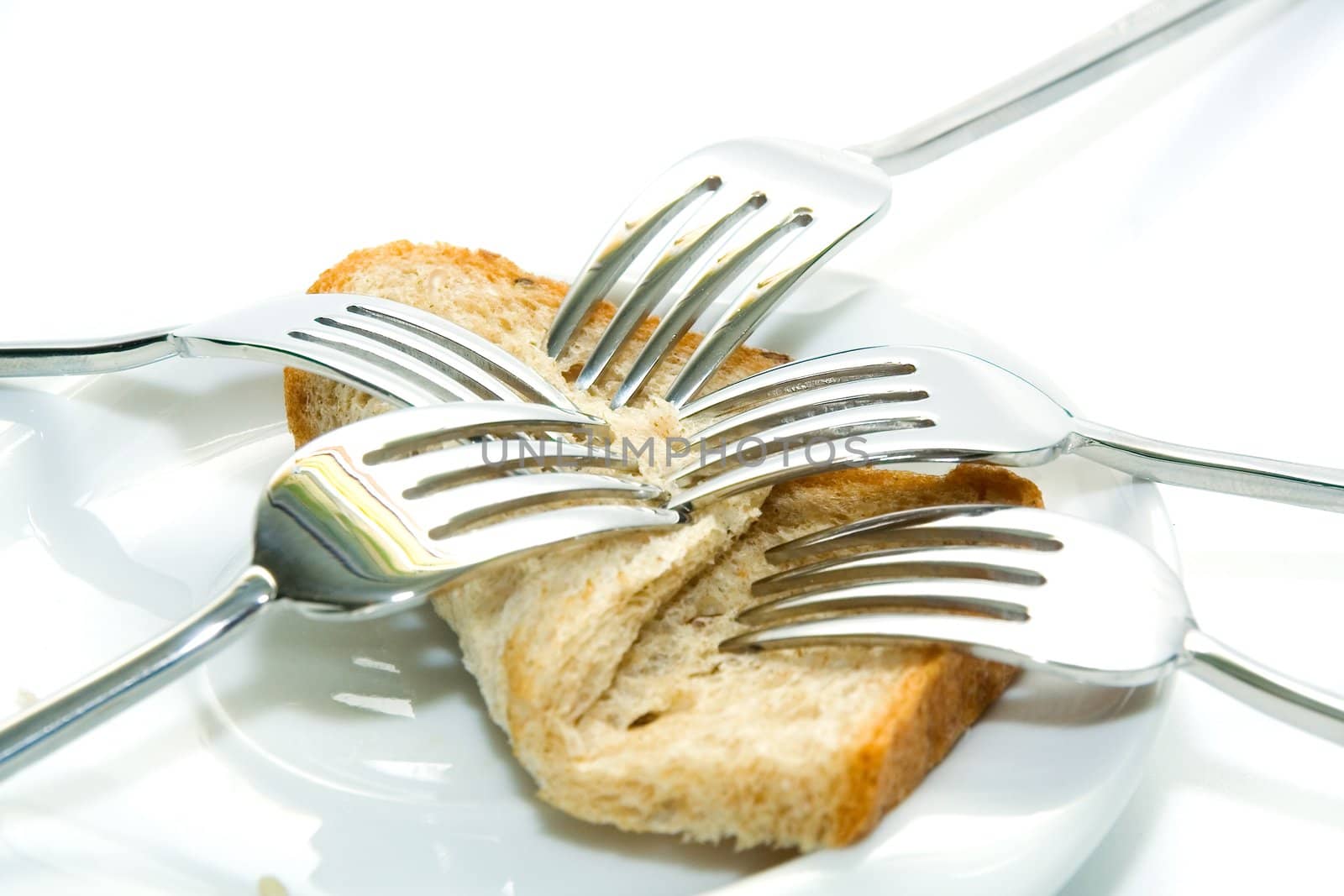 Some forks, white plateau and bread slice on a white background.  The concept of limitation of resources.
The concept  sharing between consumers
