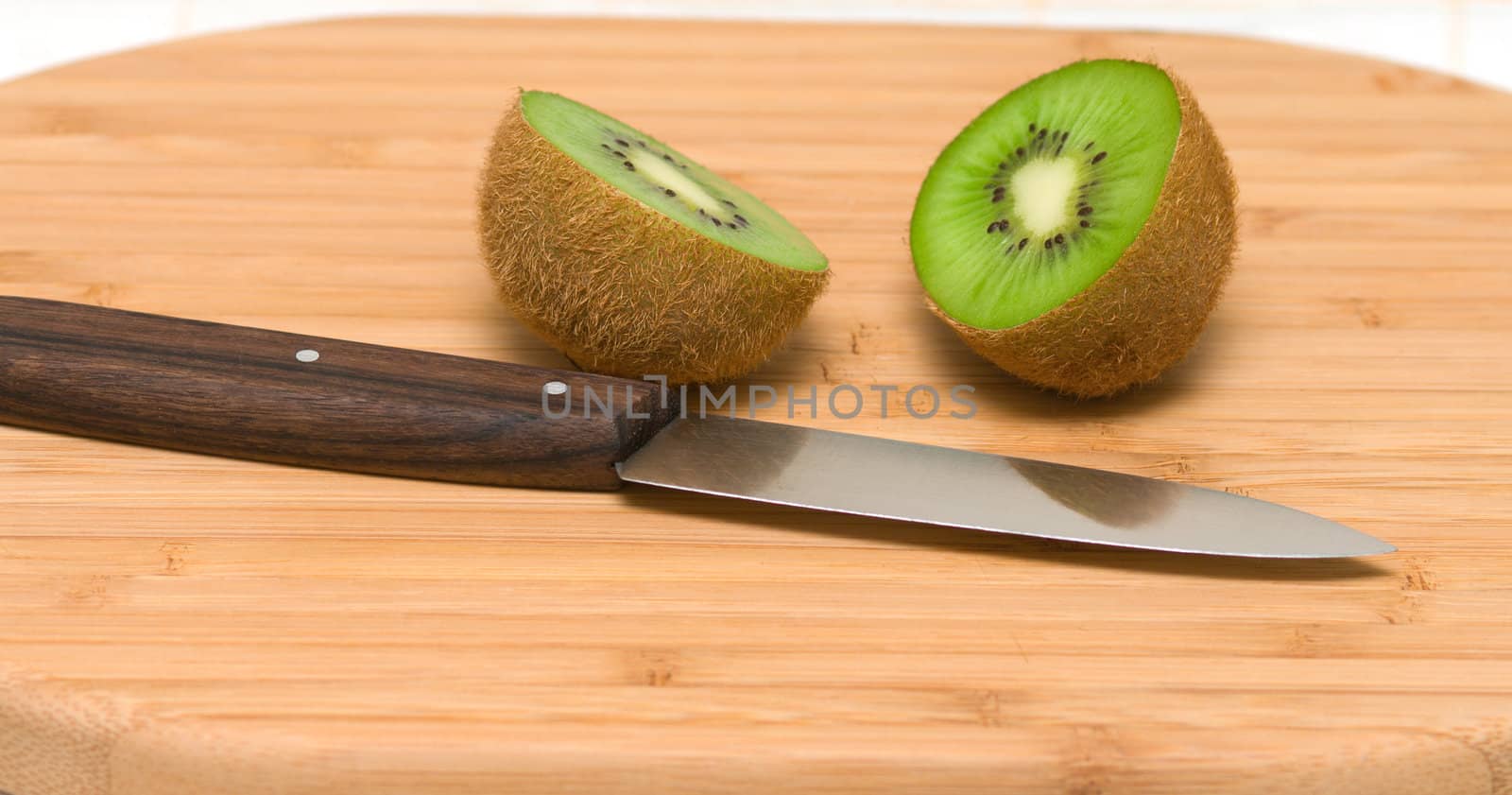 Two halves kiwi on a chopping board.