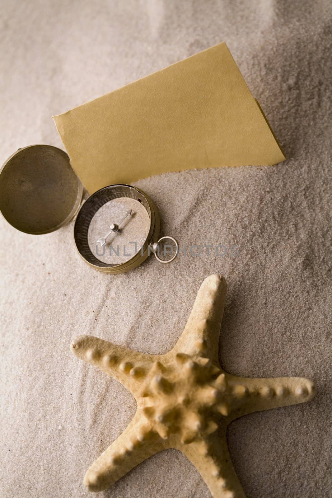 Old yellow paper and shell on sand