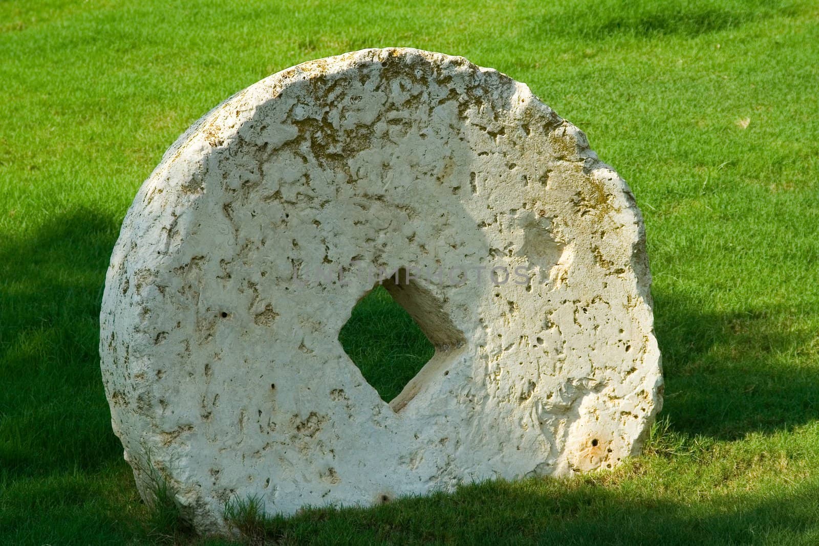 An ancient millstone were located on the grass in the natural background