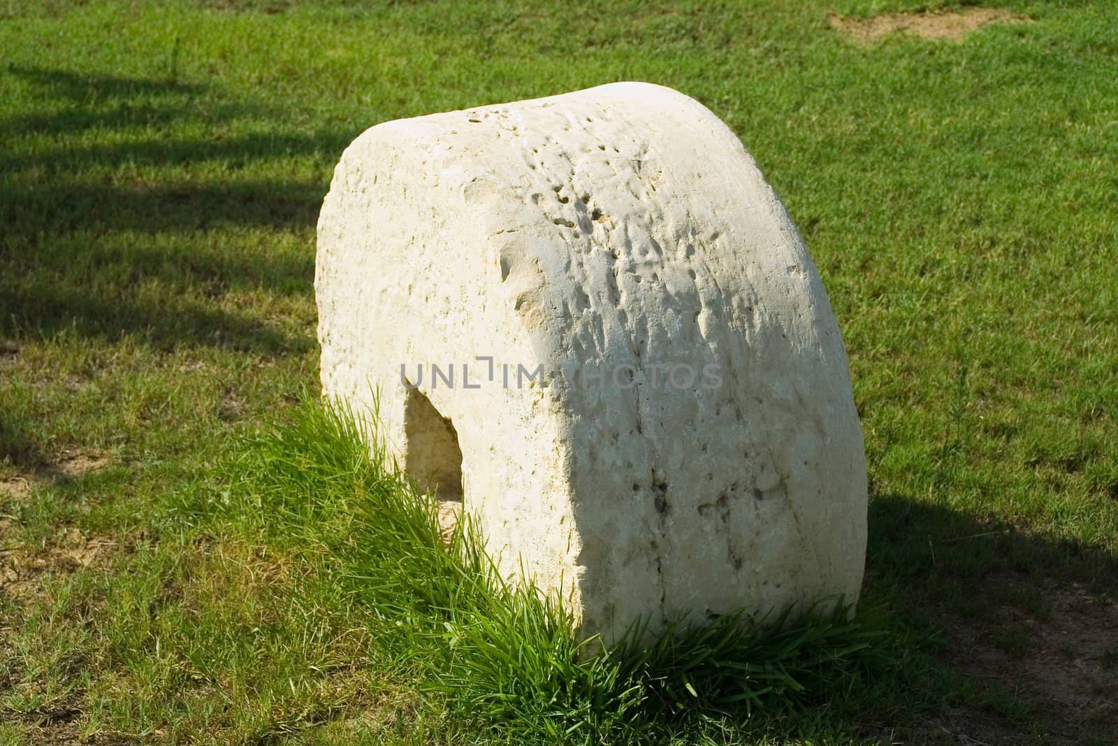 An ancient millstone were located on the grass in the natural background