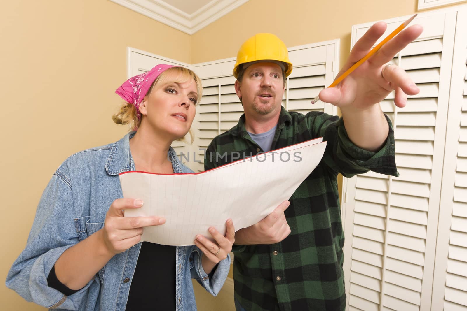 Male Contractor in Hard Hat Discussing Plans with Woman in Room.