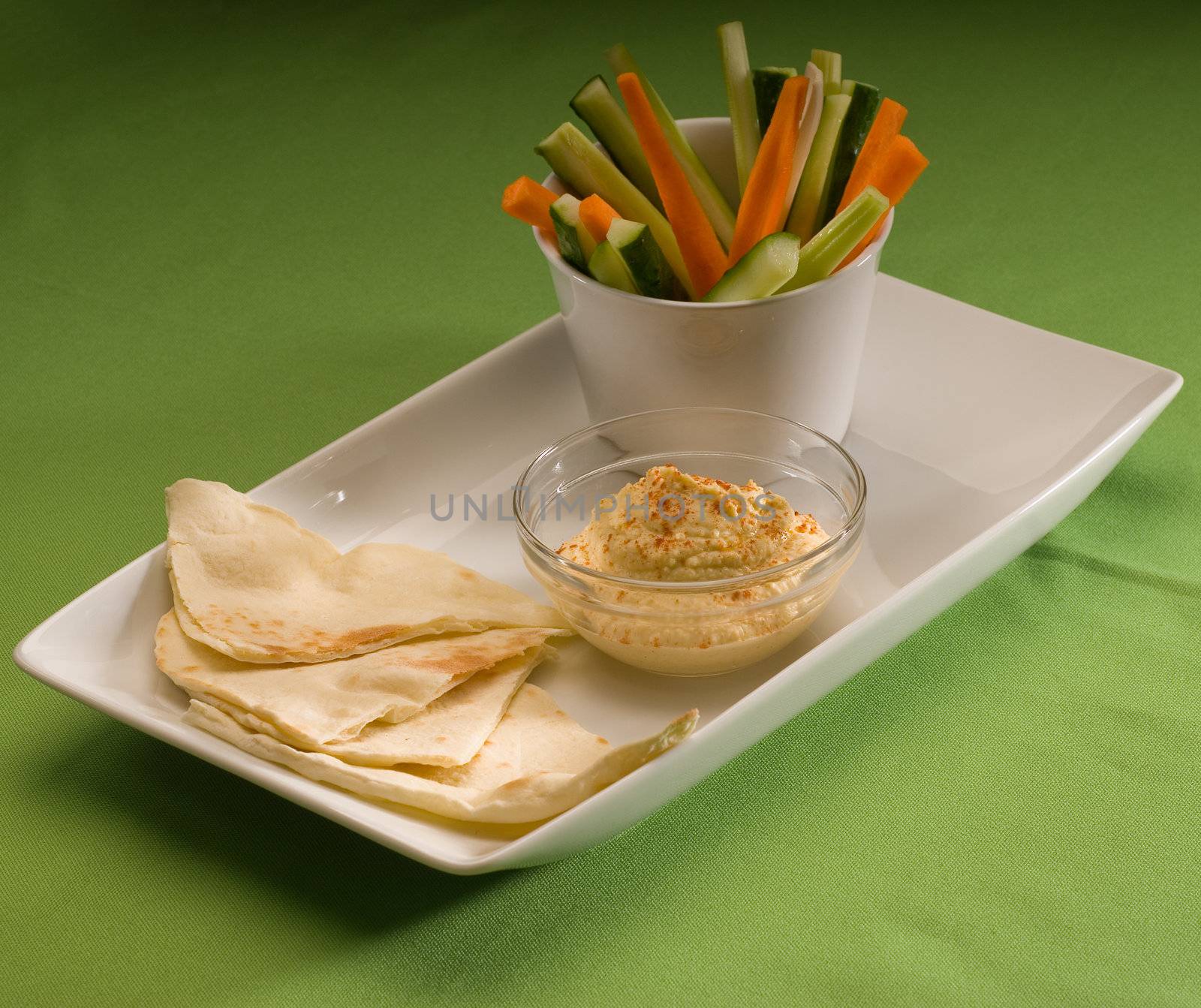 middle eastern hummus dip on a glass bowl with homemade pita brad and raw vegetable