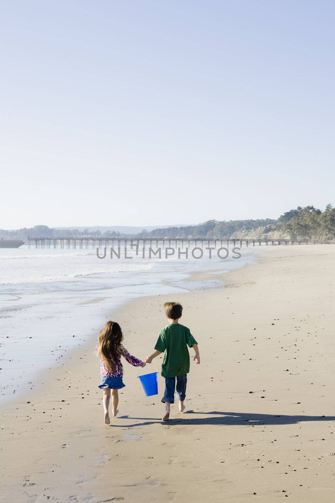 Brother and Sister with Bucket Running on the Beach