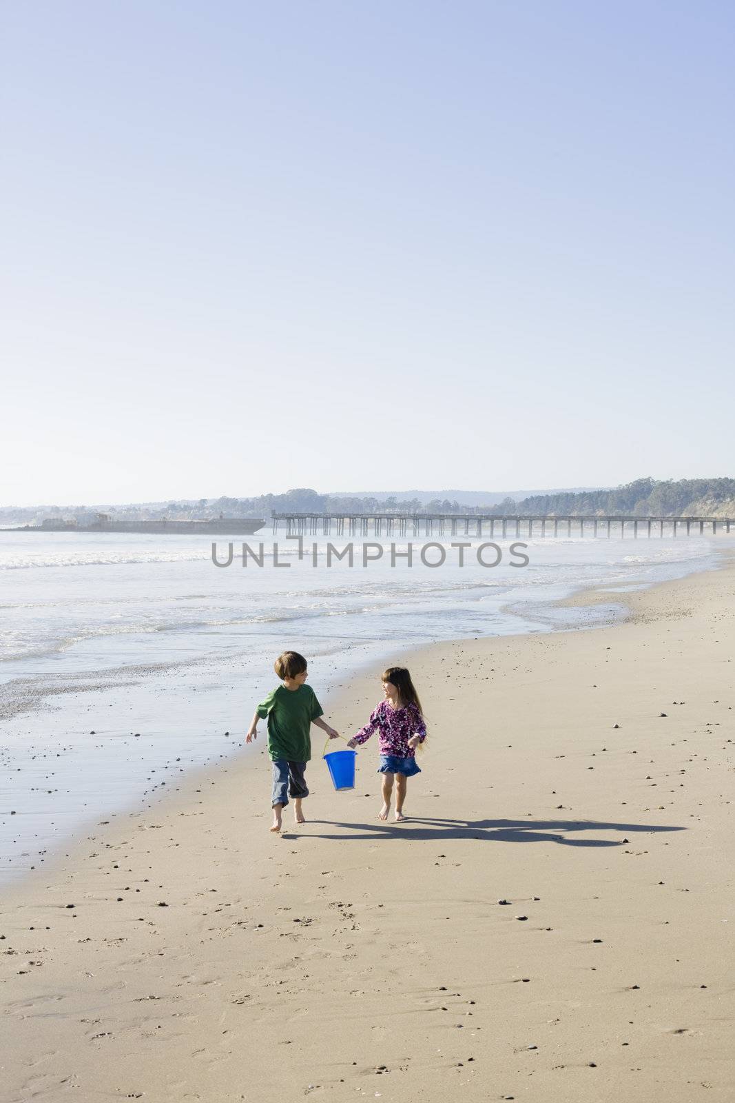 Brother and Sister with Bucket Running on the Beach