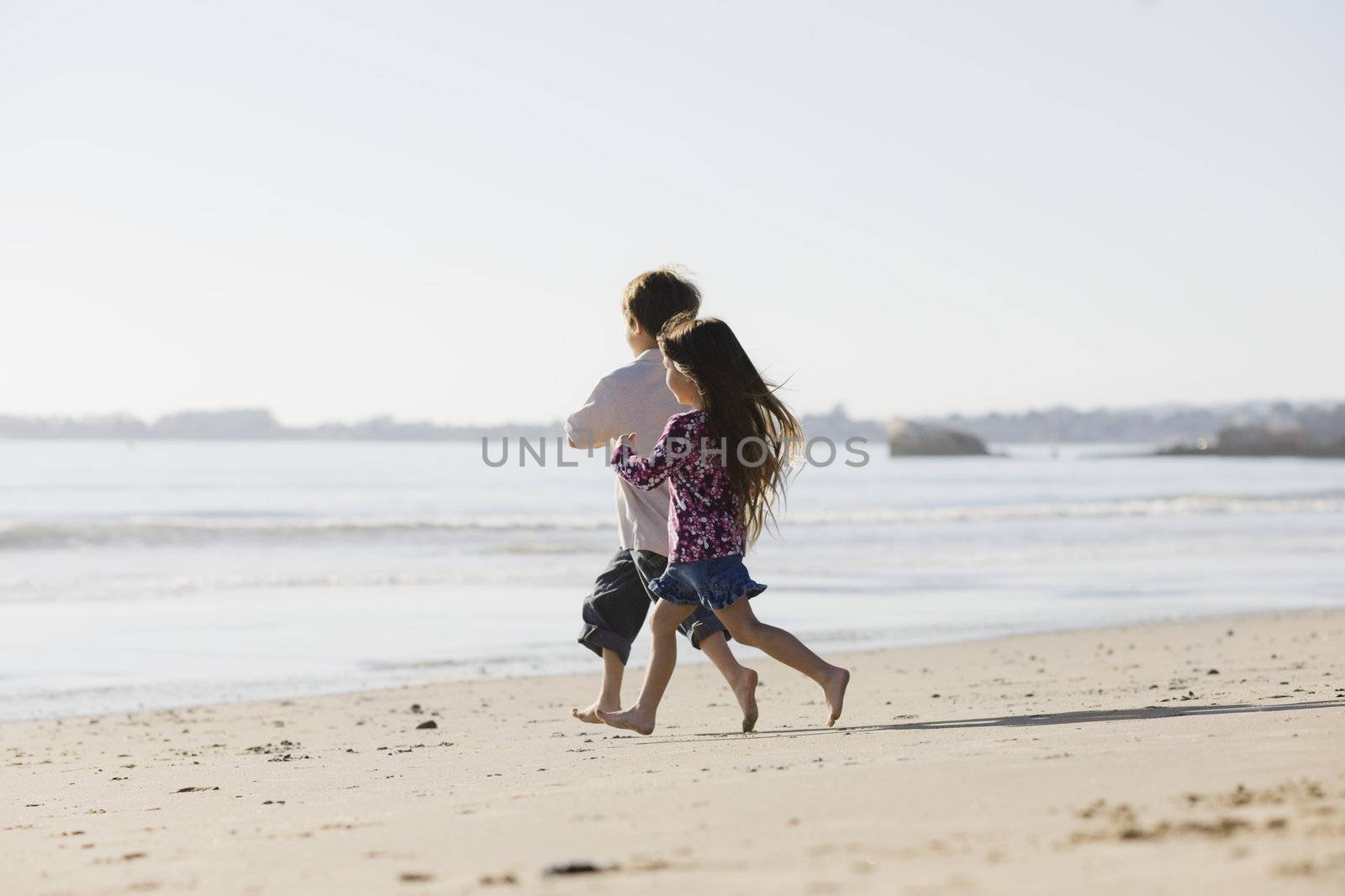 Two Kids Running Barefoot on the Sand at The Beach