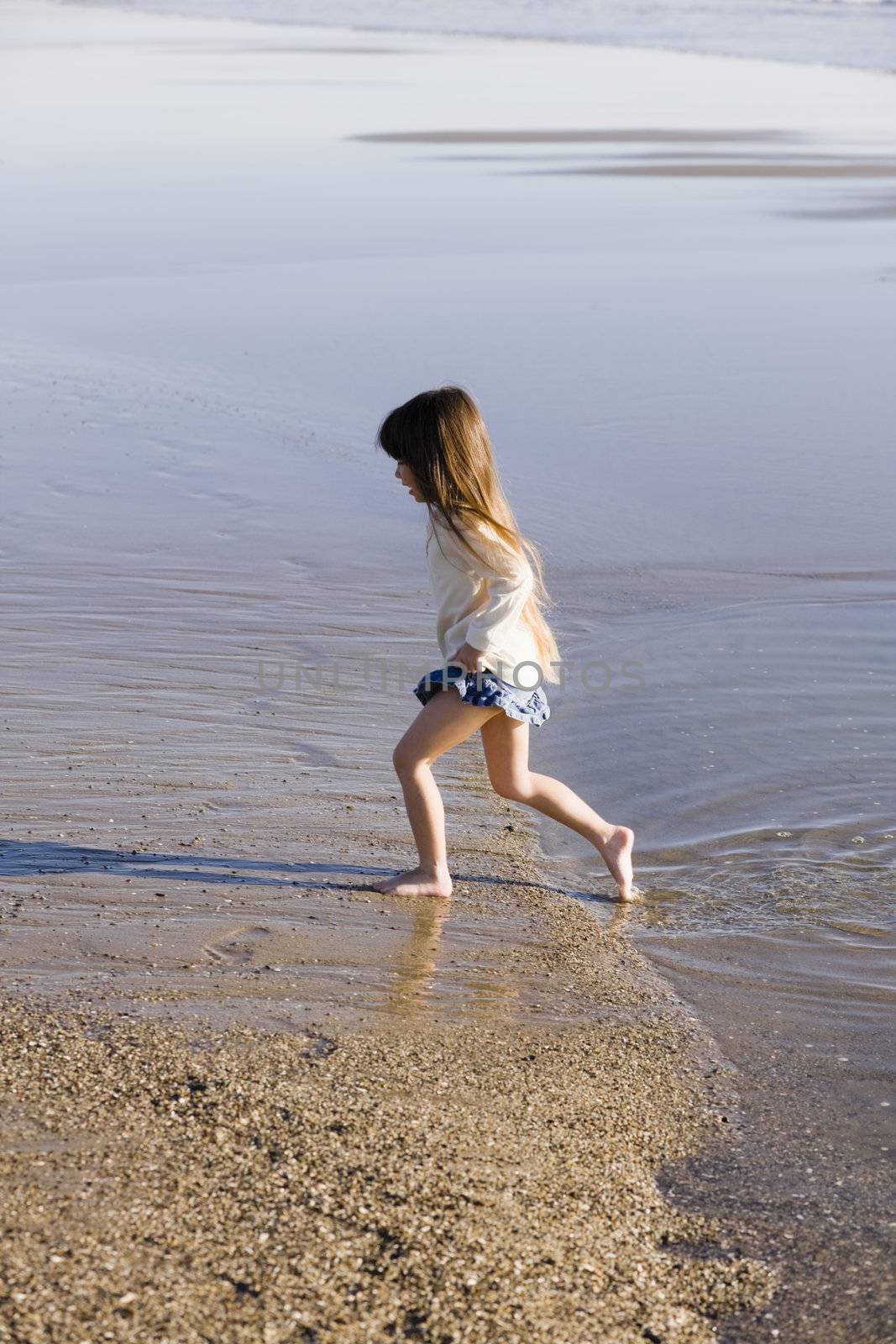 Little Girl Walking in The Water at The Beach