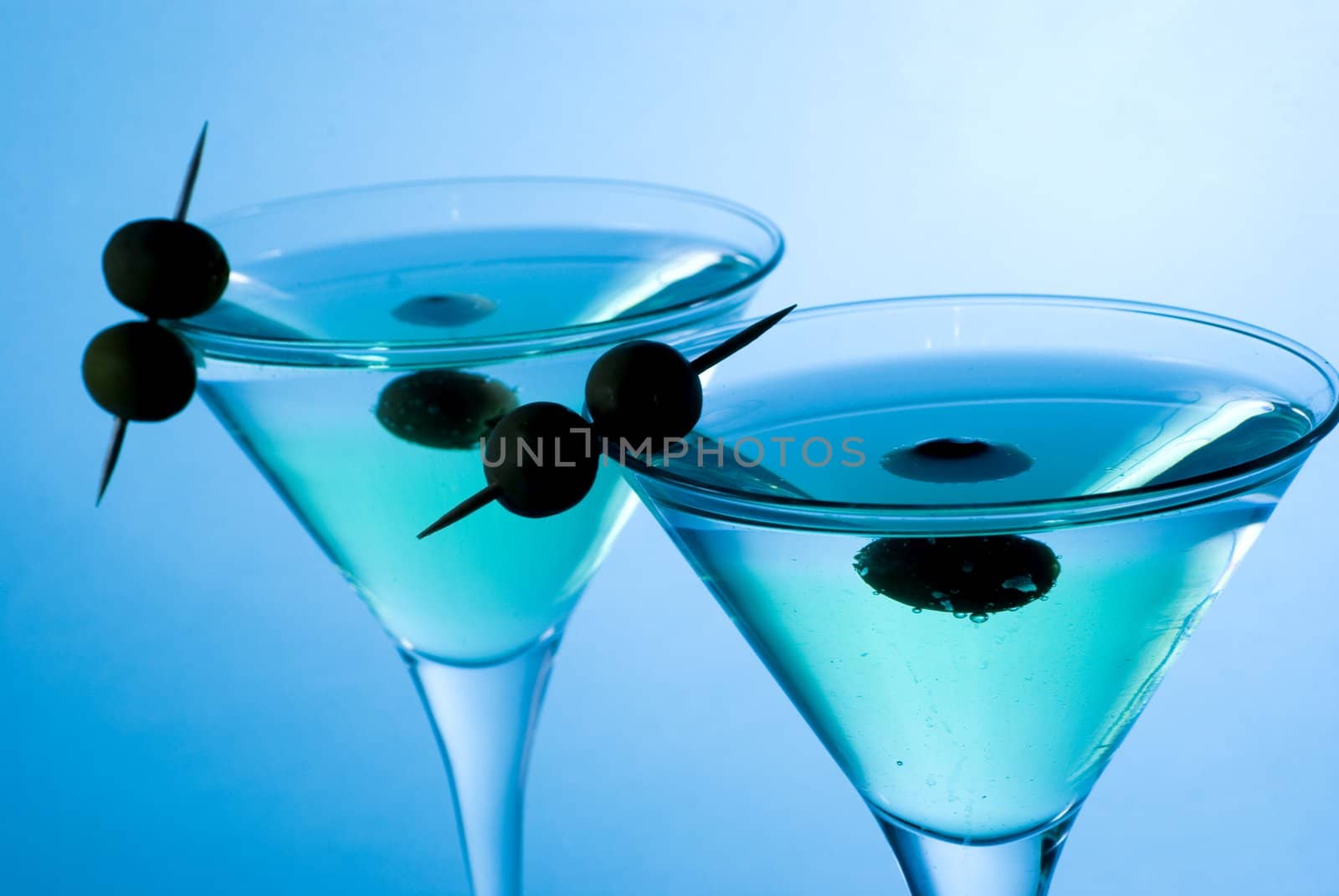 Martini cocktail with olives and blue background