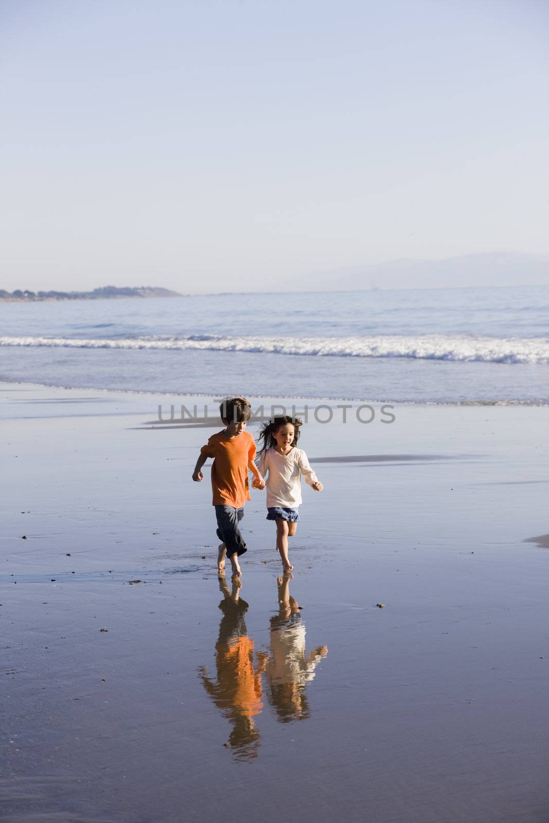 Two Little Kids Running Along the Water at The Beach