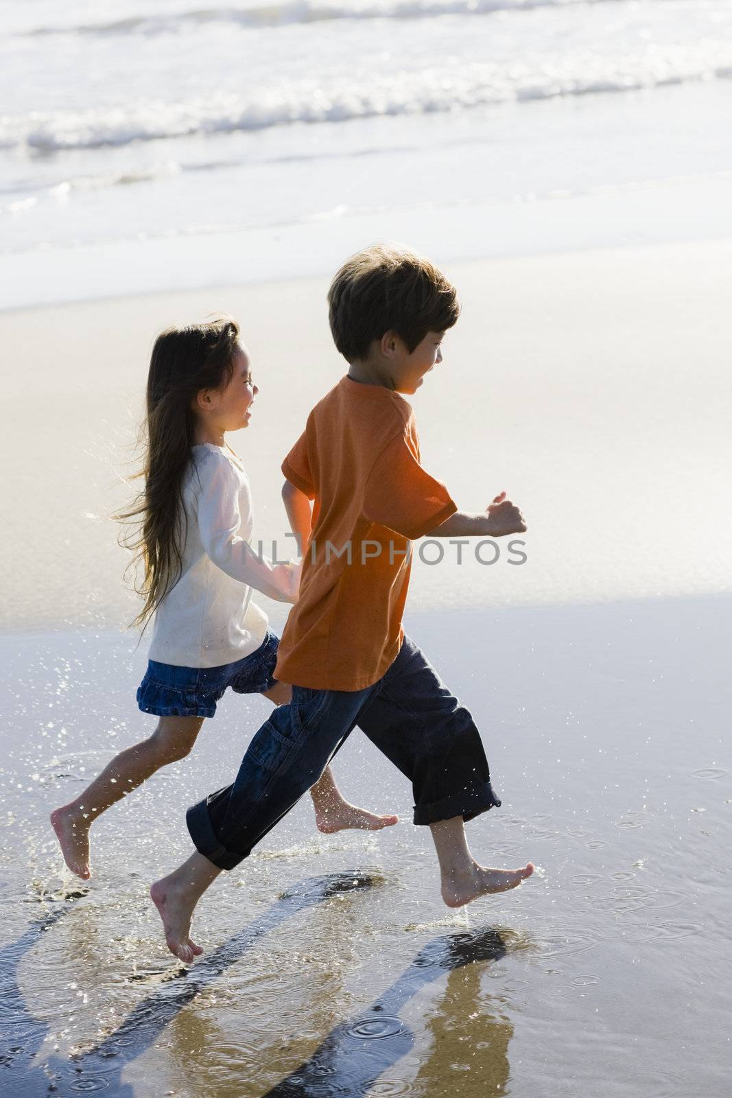 Two Little Kids Running Along the Water at The Beach