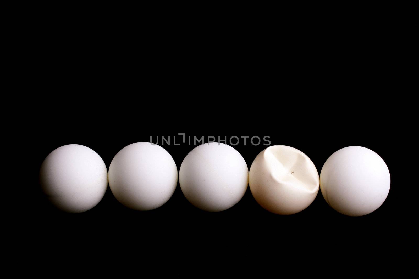 Five balls for game in table tennis on a black background. One ball is rumpled in game.