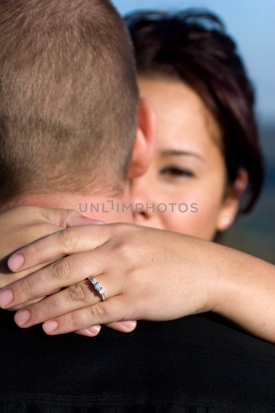 A young happy couple that just got engaged.  Shallow depth of field with focus on the diamond engagement ring.