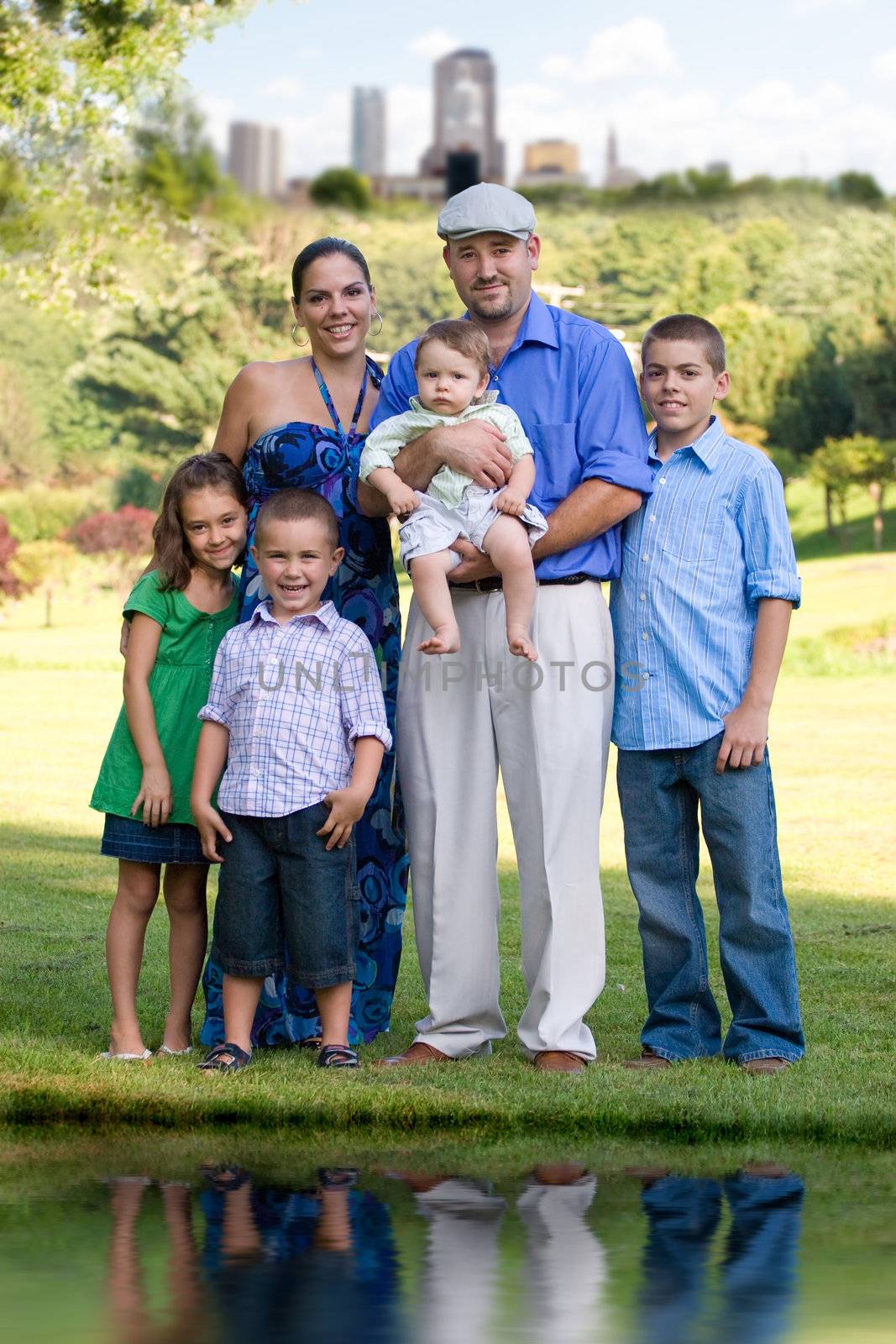 Portrait of an attractive young family with four children posing in a park outside of the city.