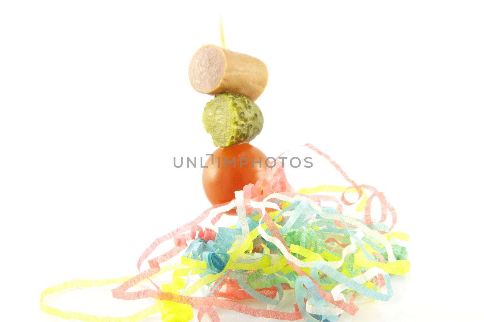 Single cocktail stick with sauage, gherkin and small red tomato with coloured streamer on a reflective white background