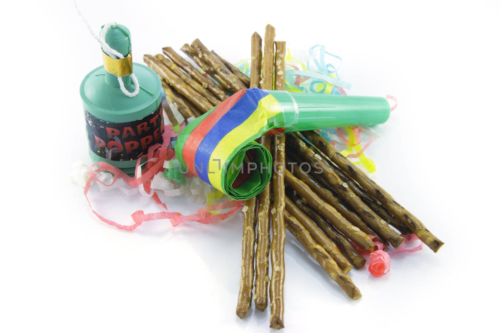 Salty brown tasty pretzels and party blower with party popper and streamers on a reflective white background